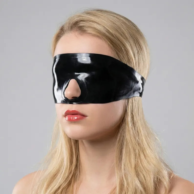 Frontal view of a model wearing a beige latex eye blindfold with an anatomical fit.