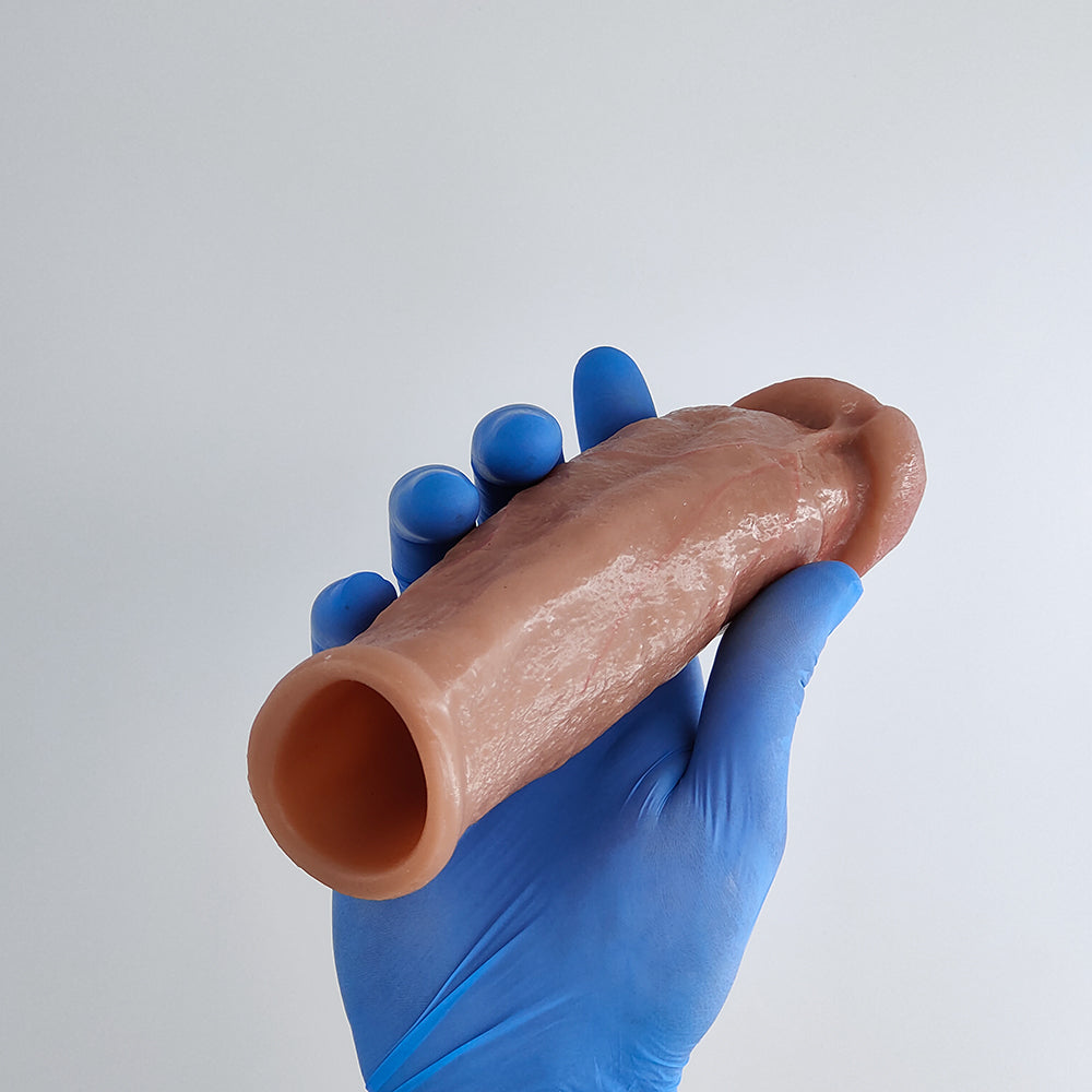 a blue gloved hand supports the realistic penis sleeve shown on the back side