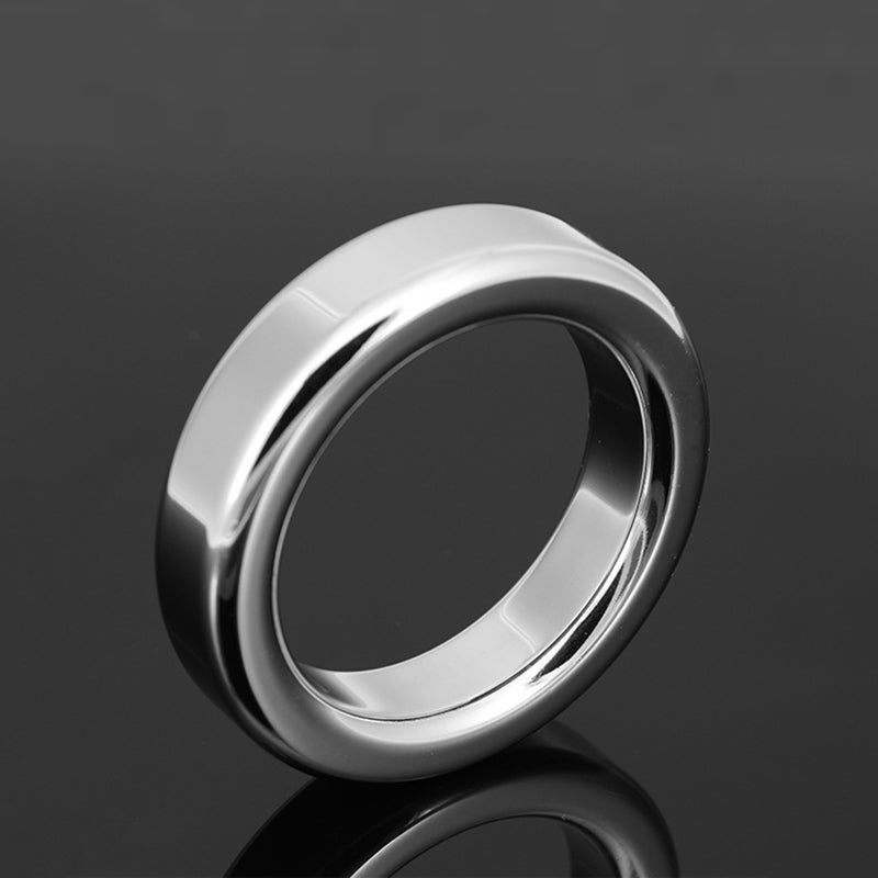Polished stainless steel cock ring on a dark reflective surface