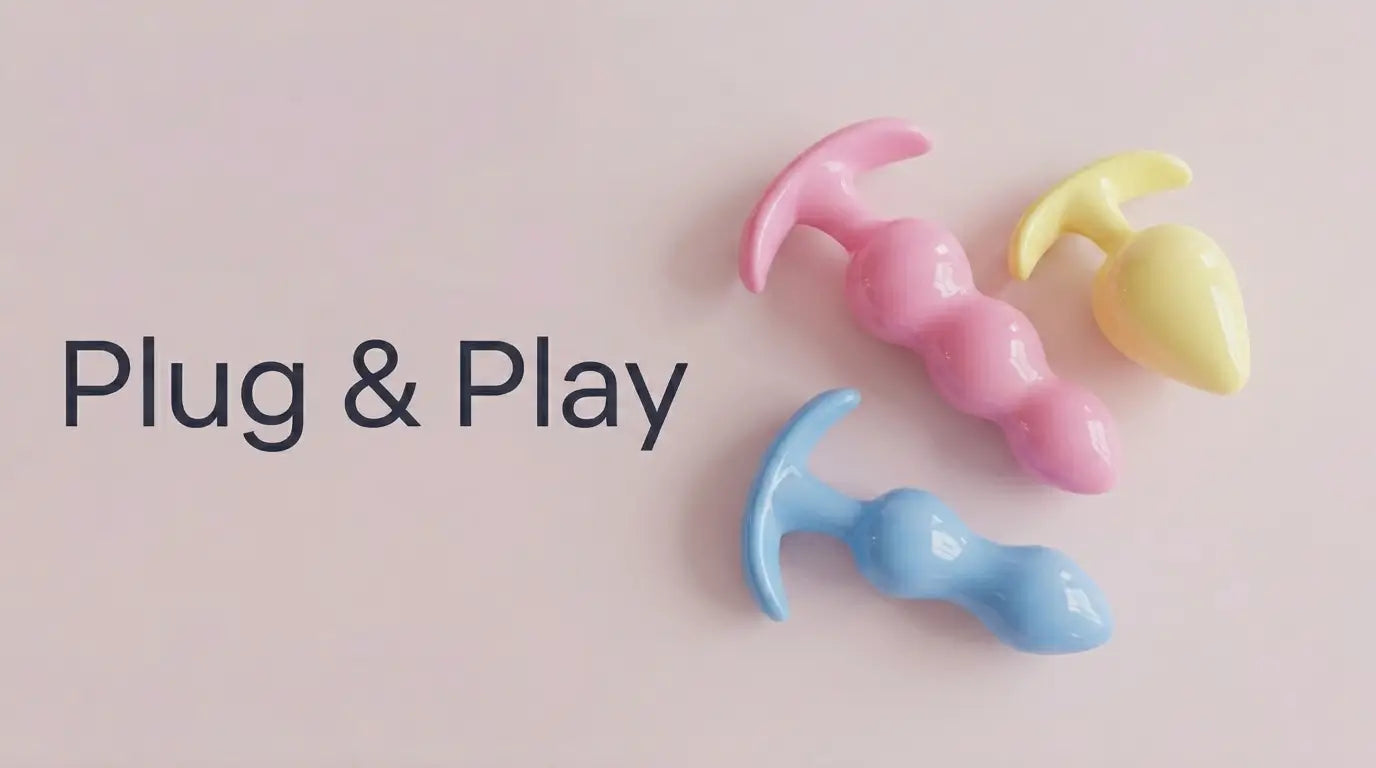 A minimalist banner for a sex shop homepage featuring the text “Plug & Play” and three anal plugs in pastel pink, light blue, and yellow on an antique pink background