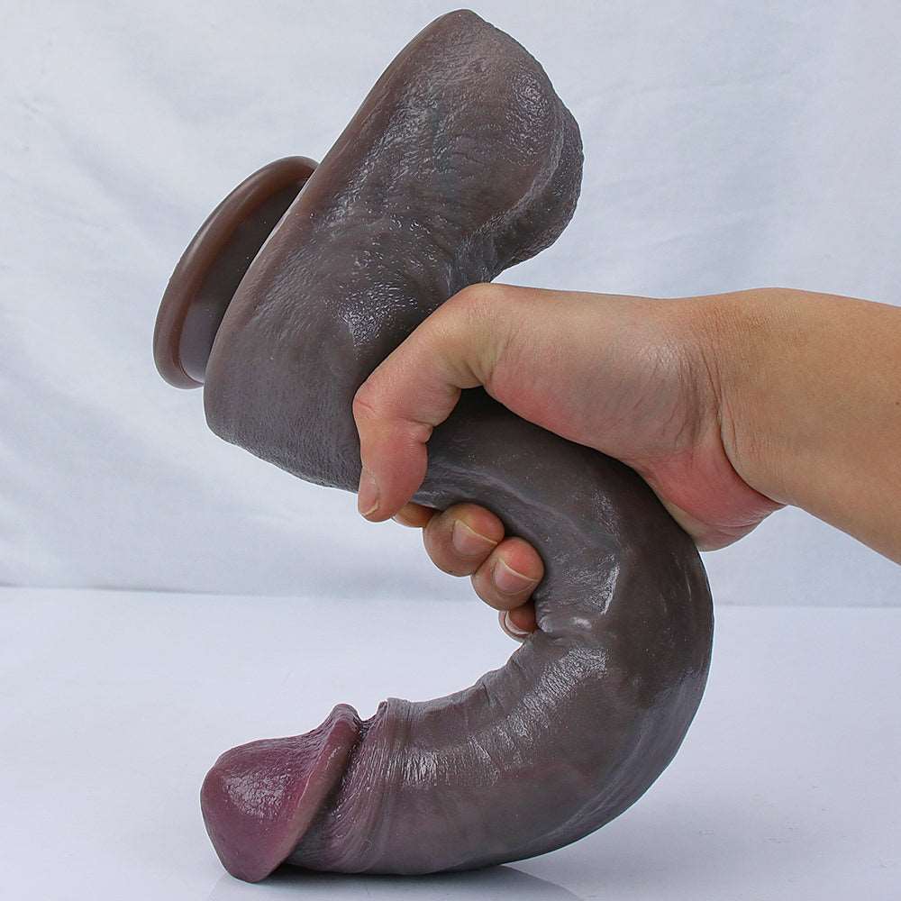 Dark brown Sculpture Black realistic dildo bent in one hand to show the soft, flexible silicone and suction cup base