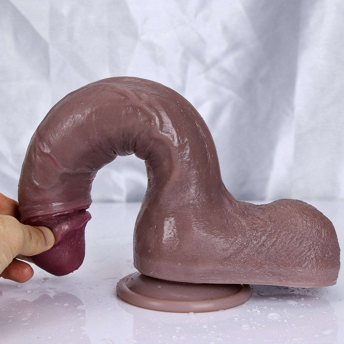Sculpture Black dual-density dildo bent into an arch on its suction cup base, held by the glans