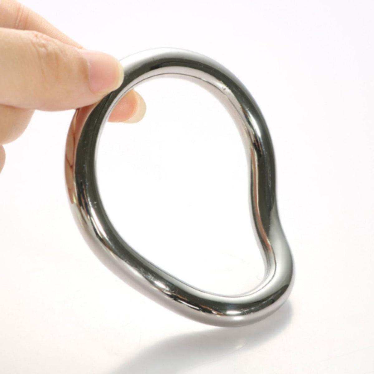 Hand holding a stainless steel curved cock ring to show its size and shape